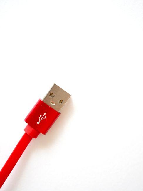 Close-up of a red USB cable against a white background with copy space, ideal for tech themes.