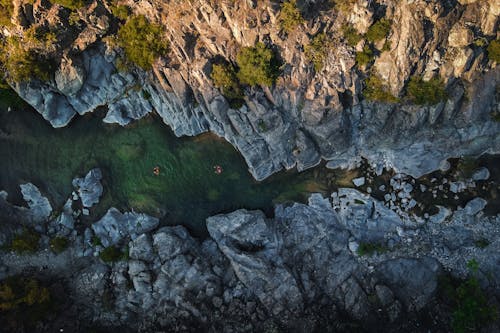 Drone view of narrow river with pure water flowing among rough rocky mountains