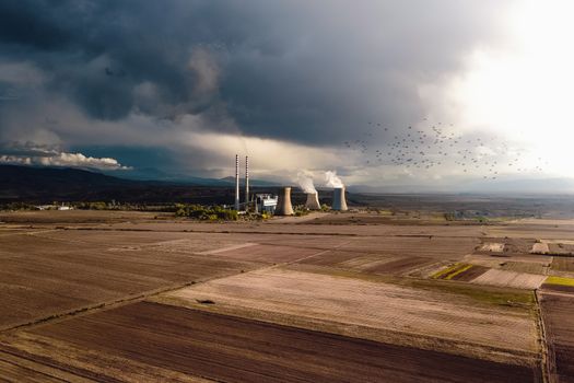 Aerial view of empty fields near atomic power station generating energy and polluting atmosphere