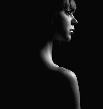 Elegant side view portrait of a woman in dramatic lighting.