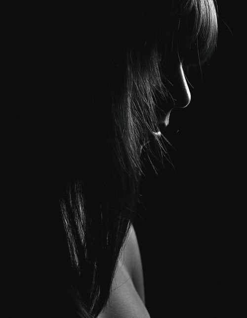 Free Moody black and white side profile portrait of a woman in shadows. Stock Photo