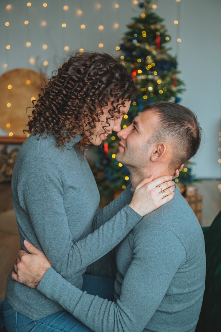 Happy Couple Embracing In Room With Christmas Decorations