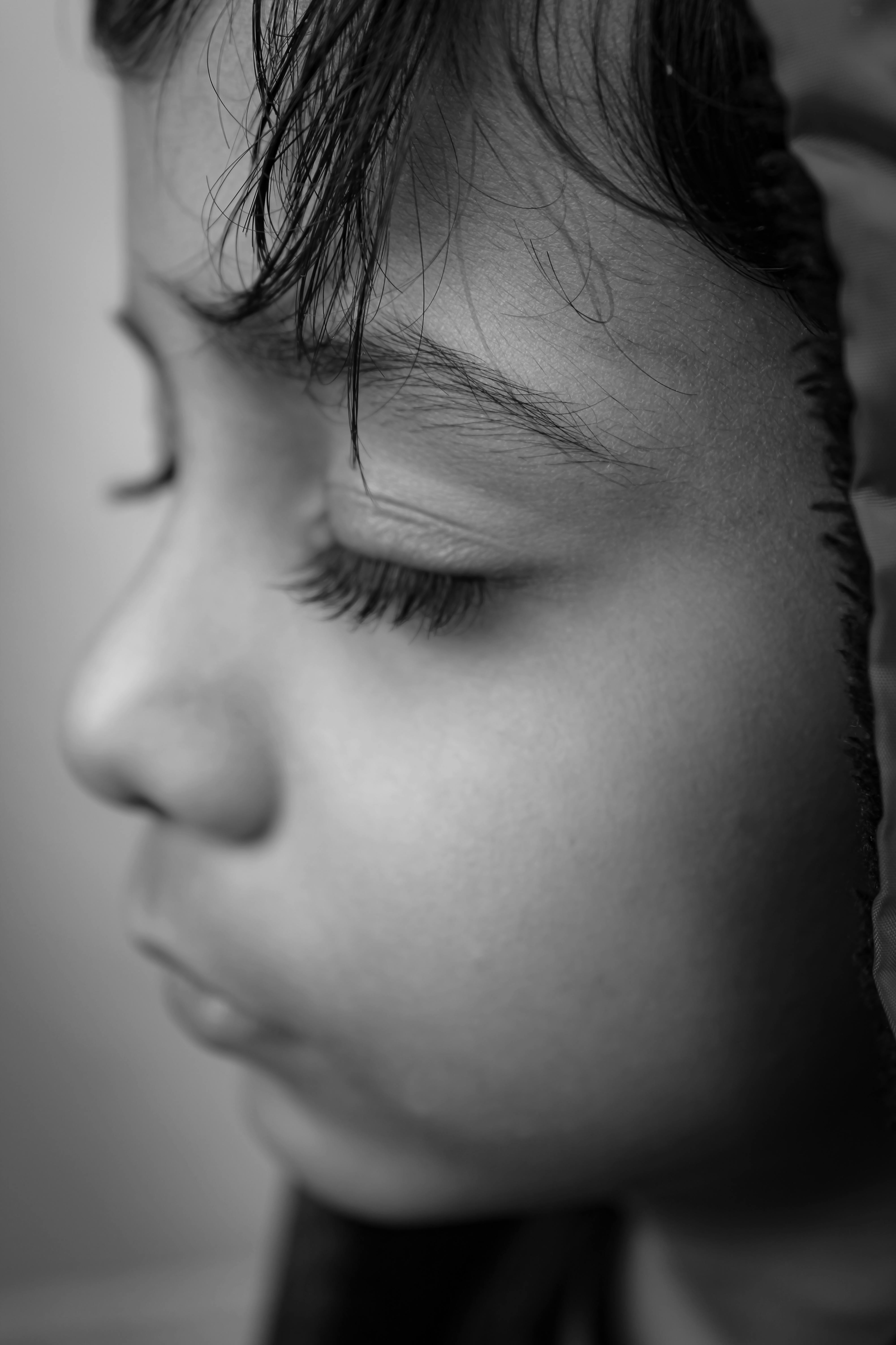 Monochromatic close-up portrait of a child's profile with closed eyes and serene expression.
