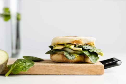 Delicious vegan breakfast sandwich with spinach and avocado on a wooden board.