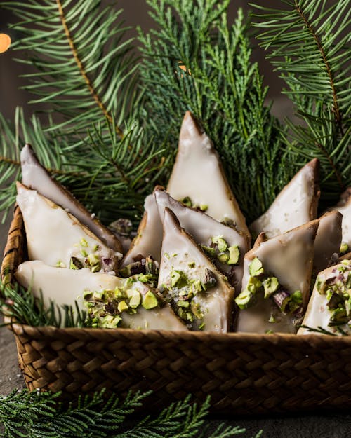 Cream Coated Cookies with Nuts Layered on Green Pine Leaves