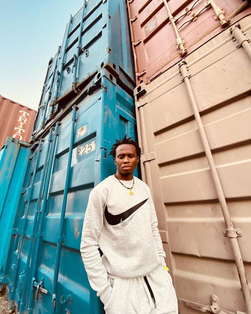 Man in White Terno Jogger Standing Beside Blue Cargo Container