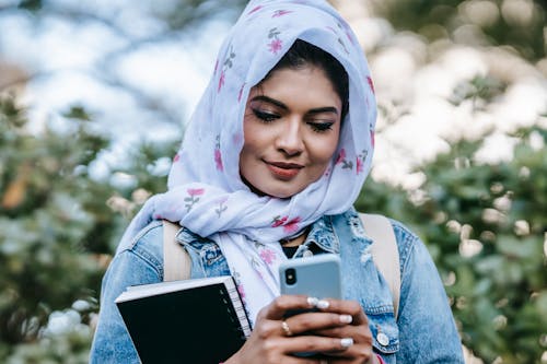 Cheerful Muslim woman with smartphone