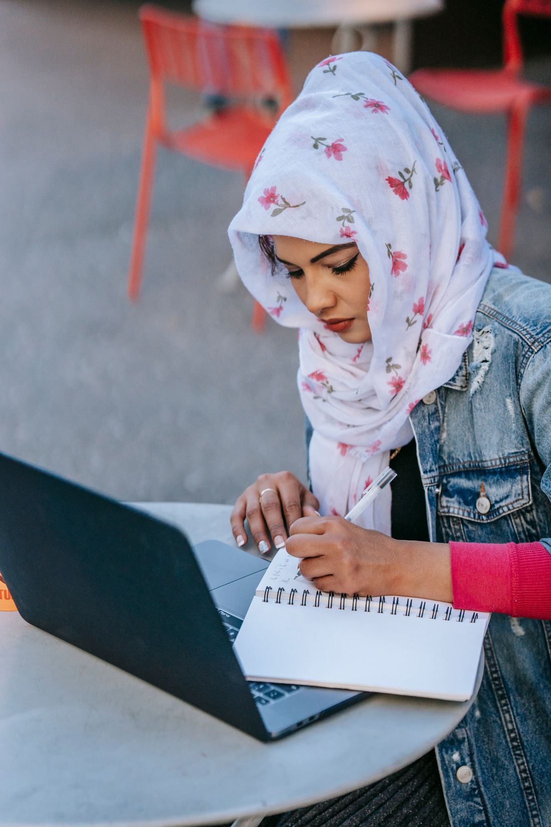 Muslim woman taking notes while learning online