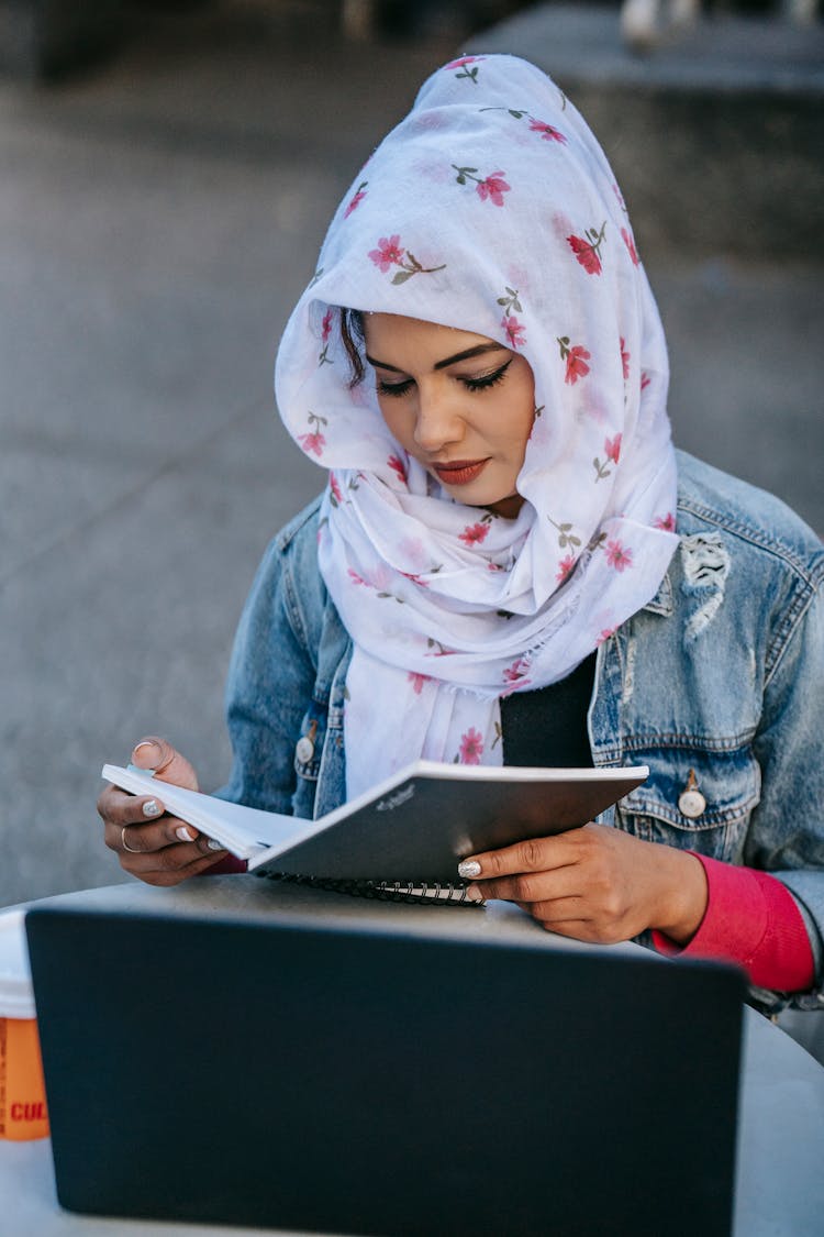 Focused Woman Reading Notes In Notebook