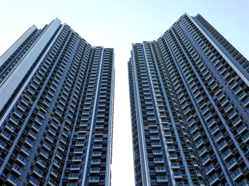 From below of similar contemporary high rise residential buildings with balconies under blue sky