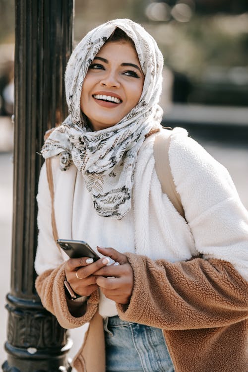 Happy stylish ethnic lady smiling on city street