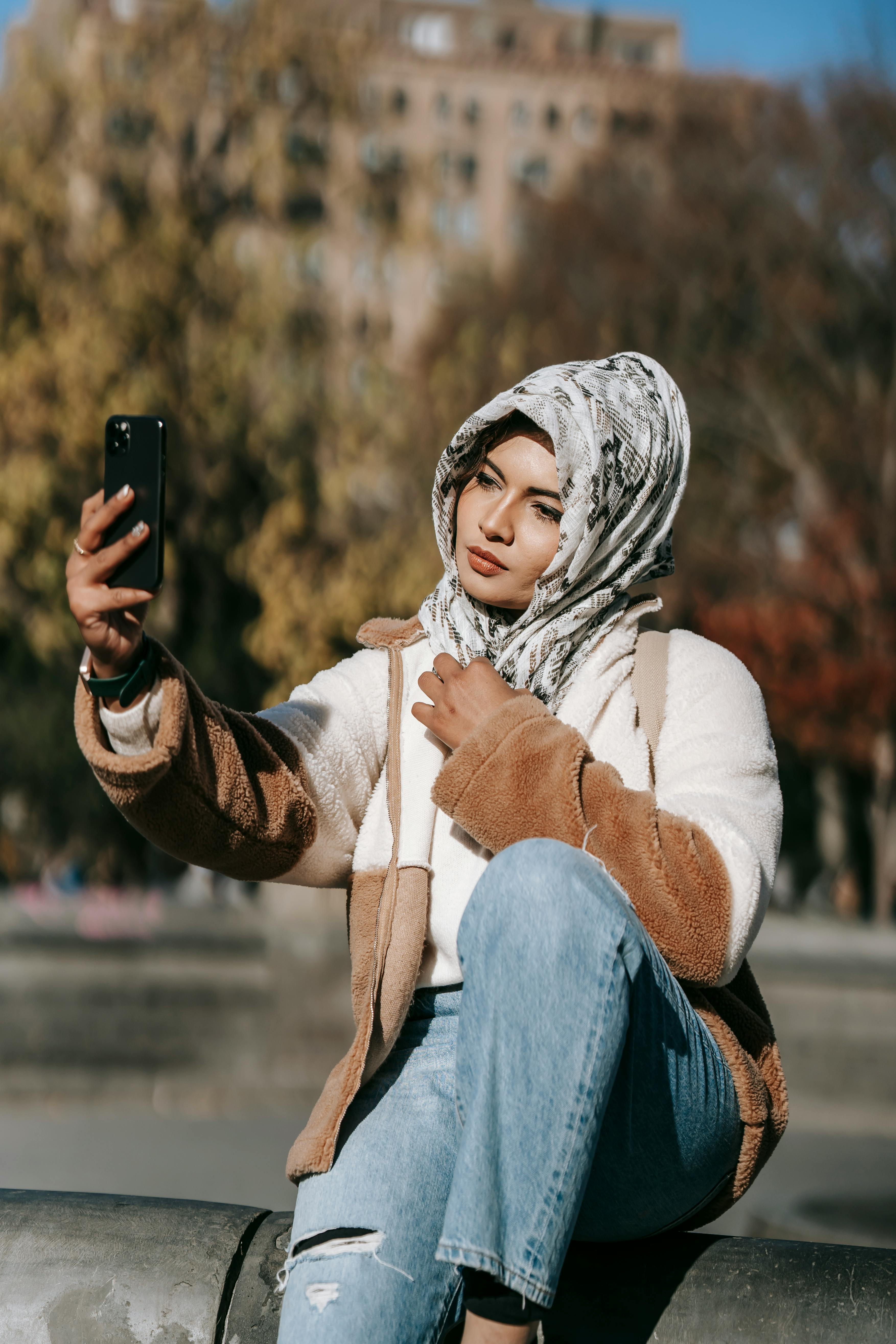 trendy young muslim lady taking selfie in city park