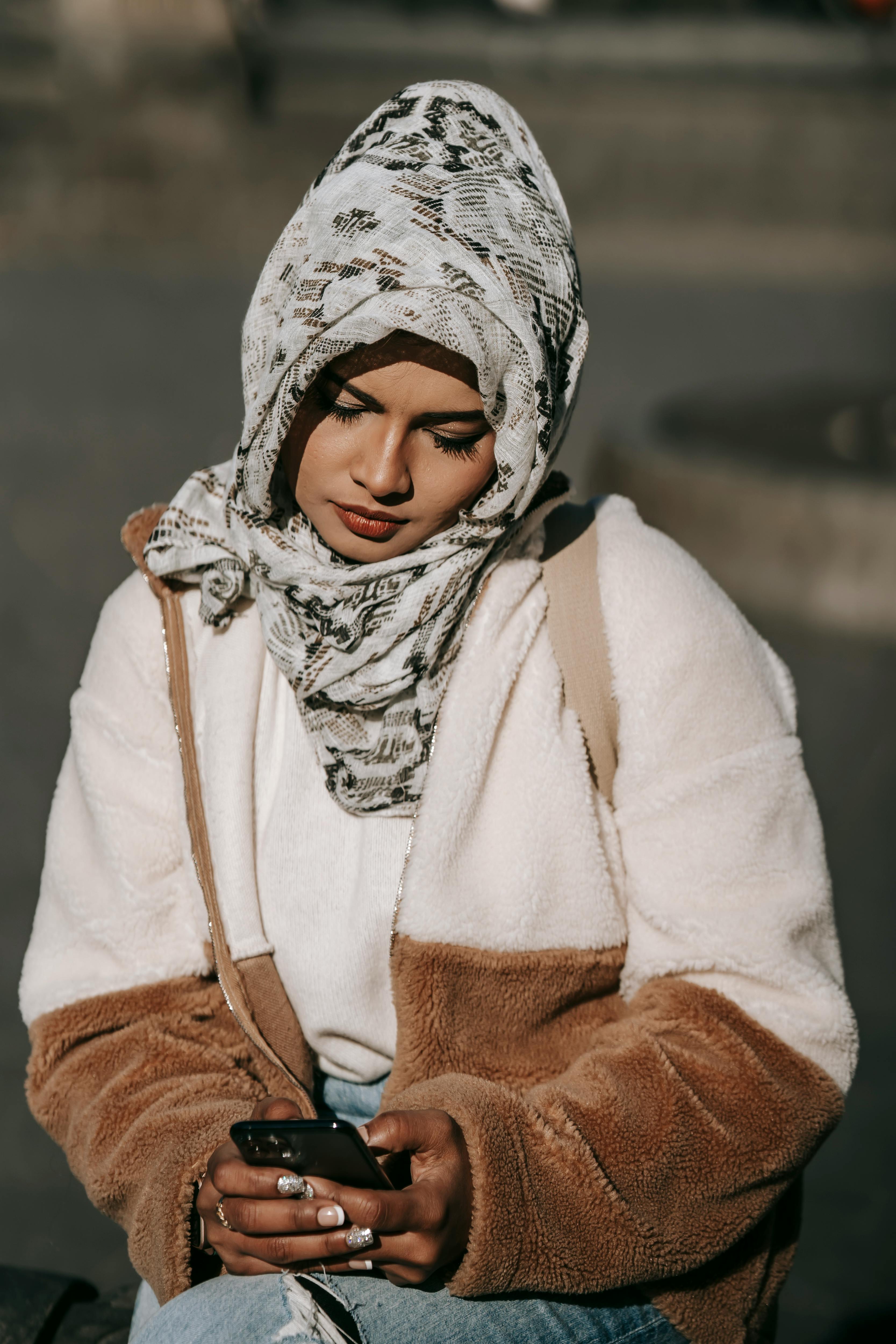 dreamy young ethnic female millennial browsing smartphone on street