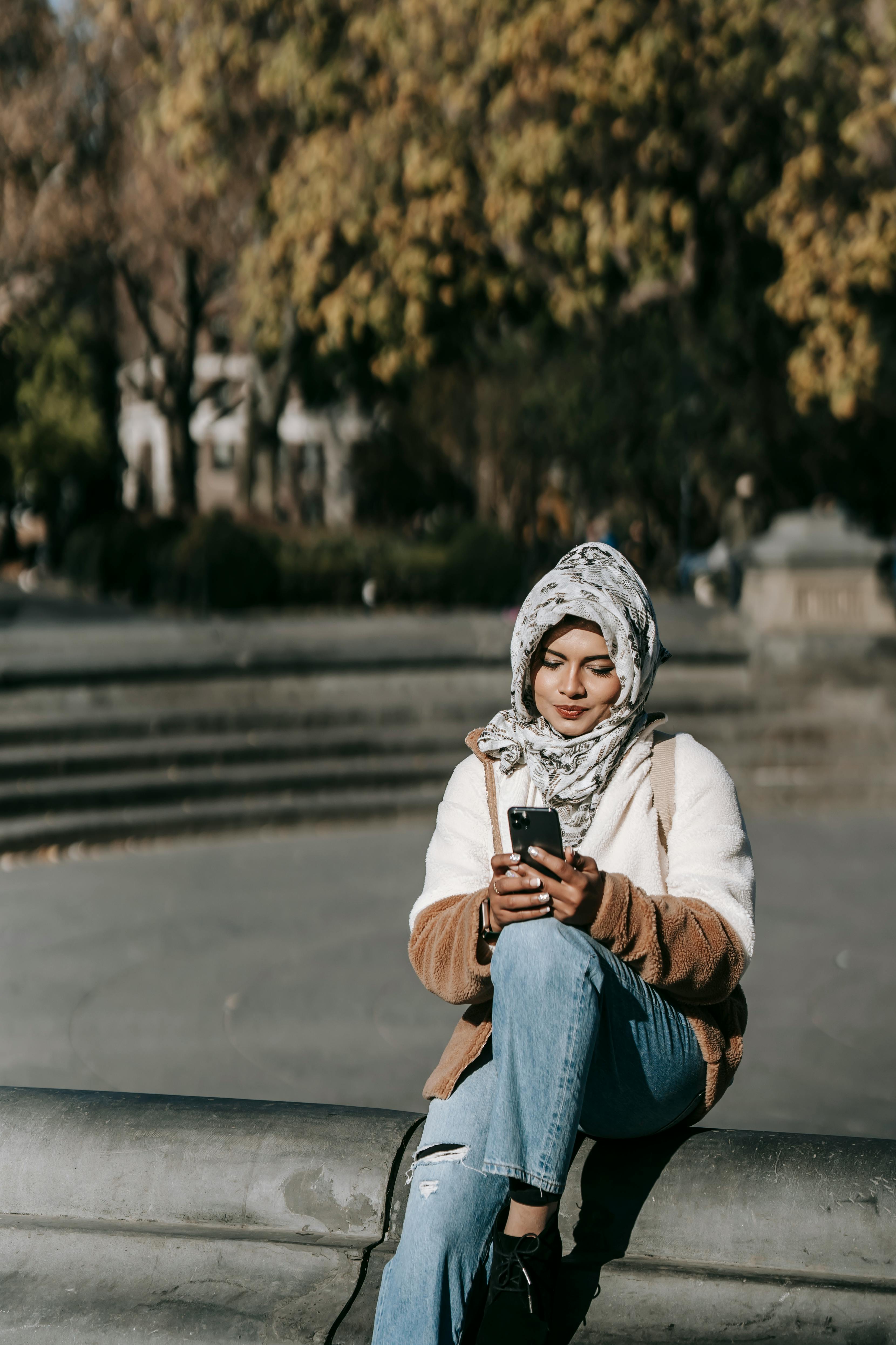 content young ethnic lady messaging on mobile phone in autumn park