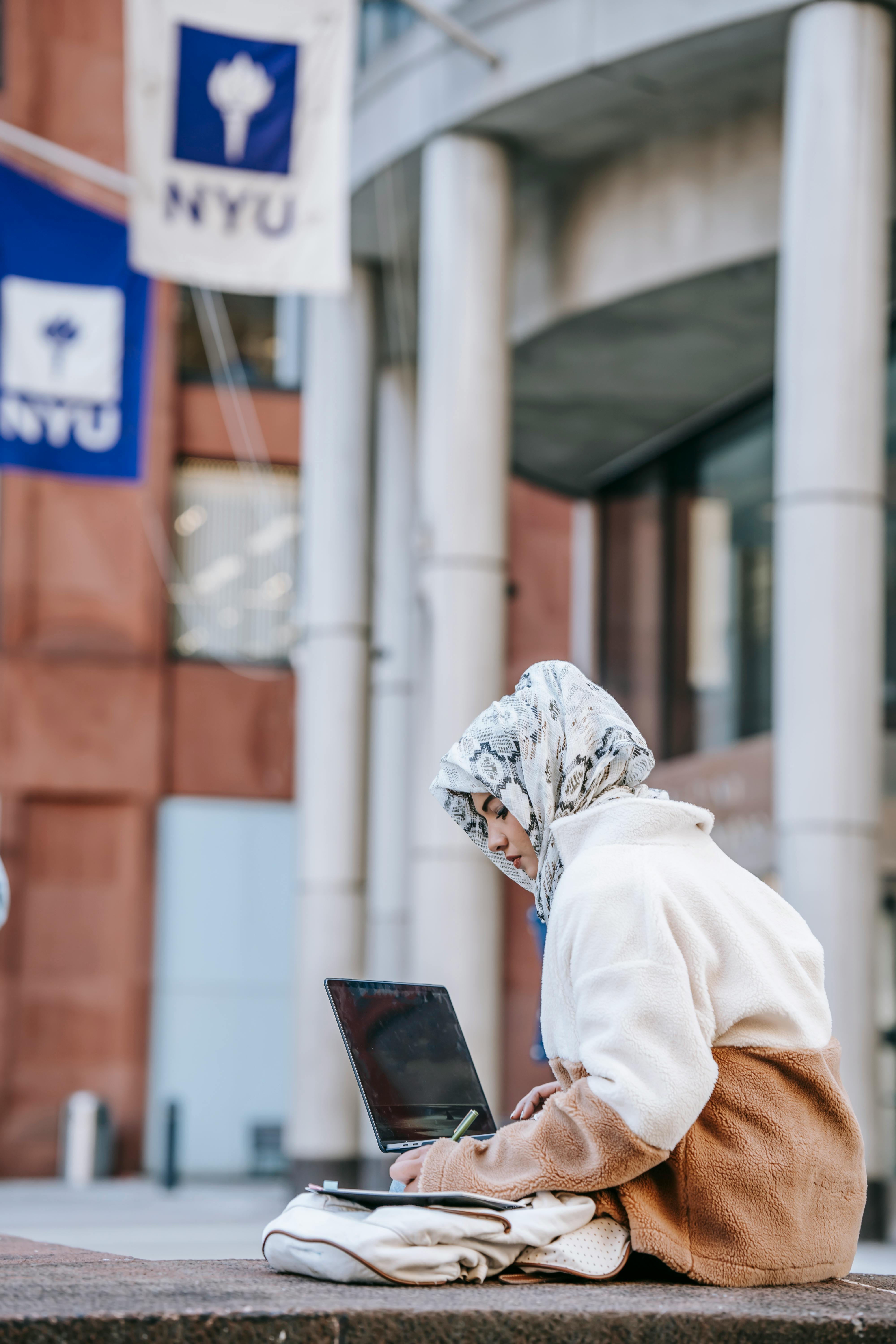 serious young arab woman doing assignment near university building