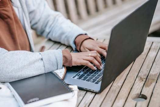 A freelancer working on a laptop at an outdoor wooden table, focusing on productivity and remote work.