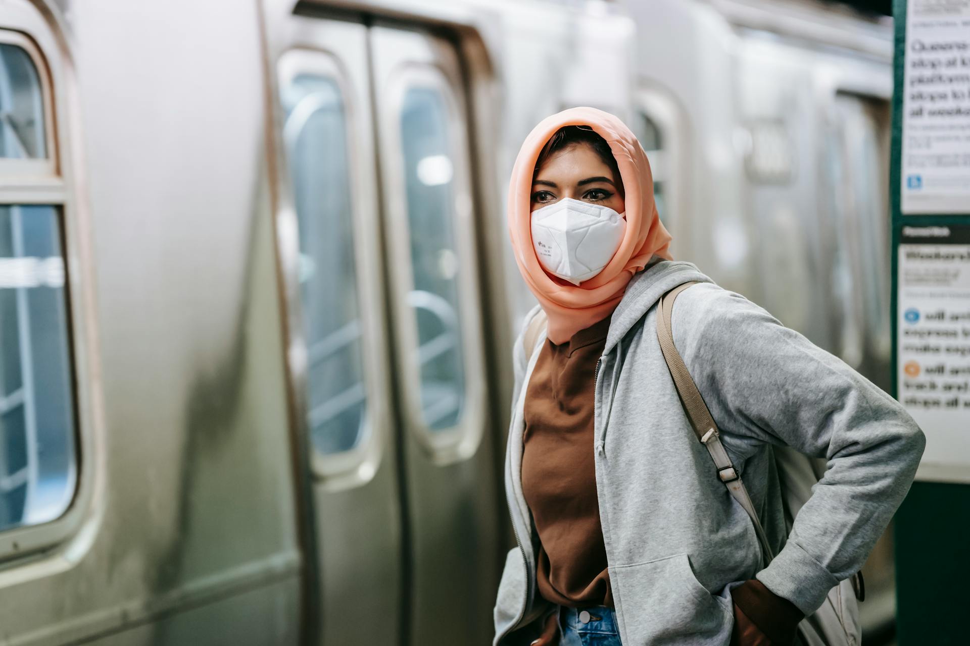 Young Muslim female in casual wear and traditional headscarf with protective mask on subway platform