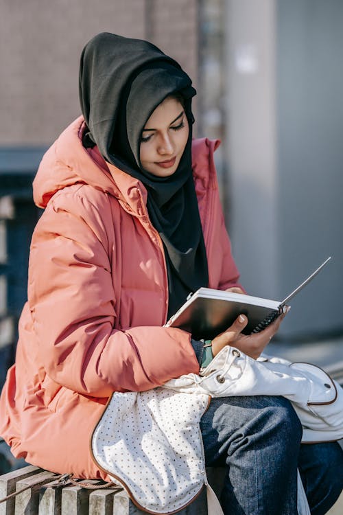 Focused female student reading notepad on street