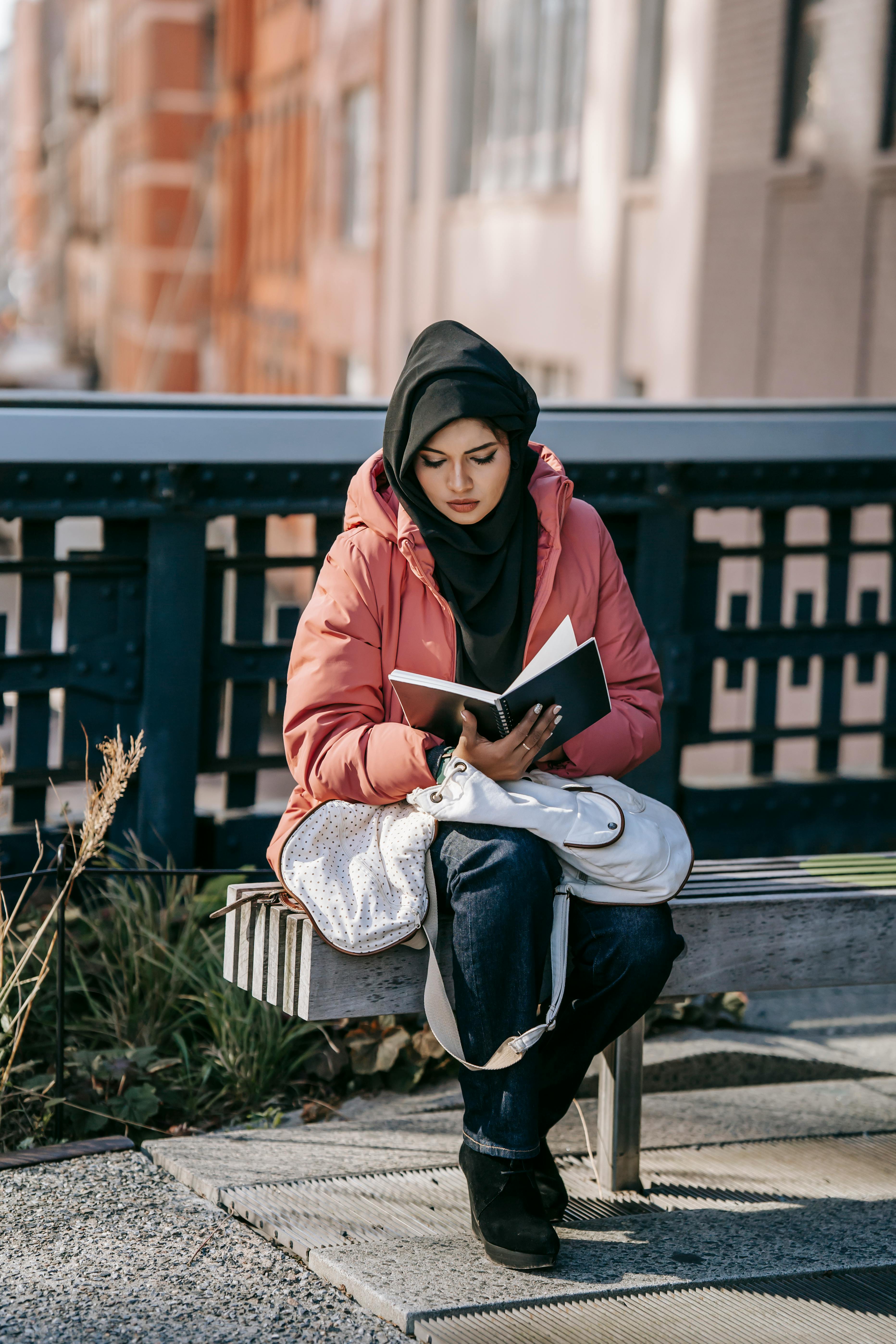 serious woman reading book while resting on bench