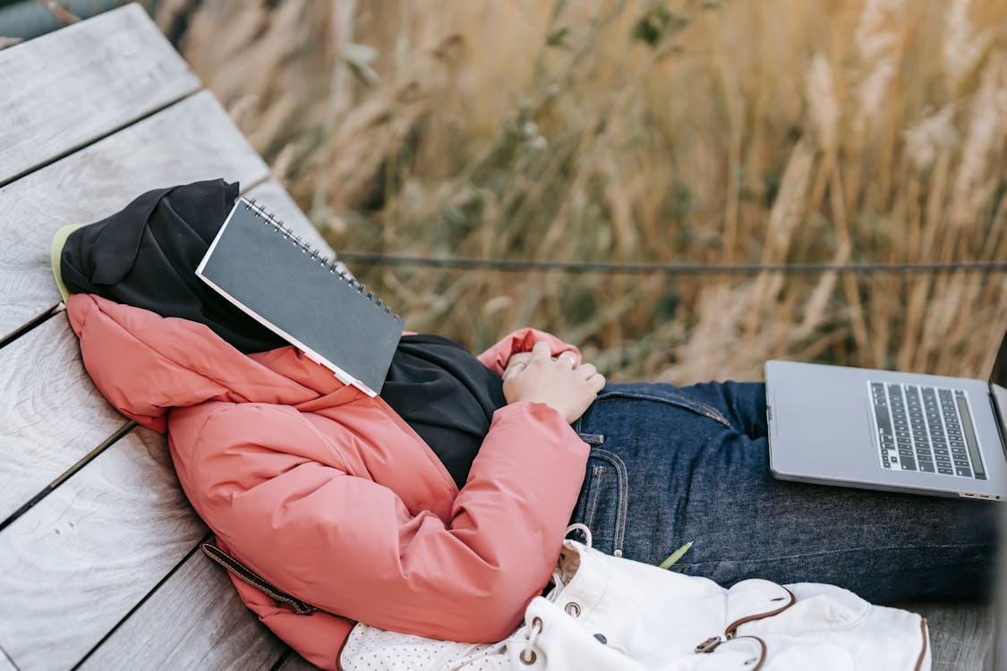 Muslim woman in hijab resting with notebook on face