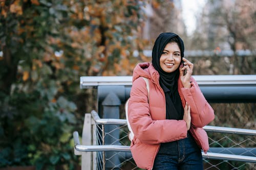 Vrouw In Roze Jasje En Blauwe Denimjeans Zittend Op Witte Houten Bank