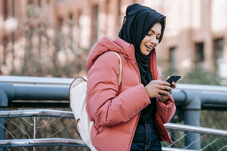 Muslim Smiling Ethnic Woman In Hijab Checking Smartphone