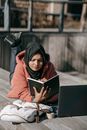 Muslim woman reading book while lying on street in sunny day