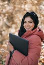Satisfied ethnic female student with laptop in hands in park