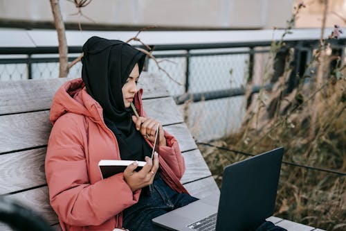 Free Ethnic lady using computer in street Stock Photo