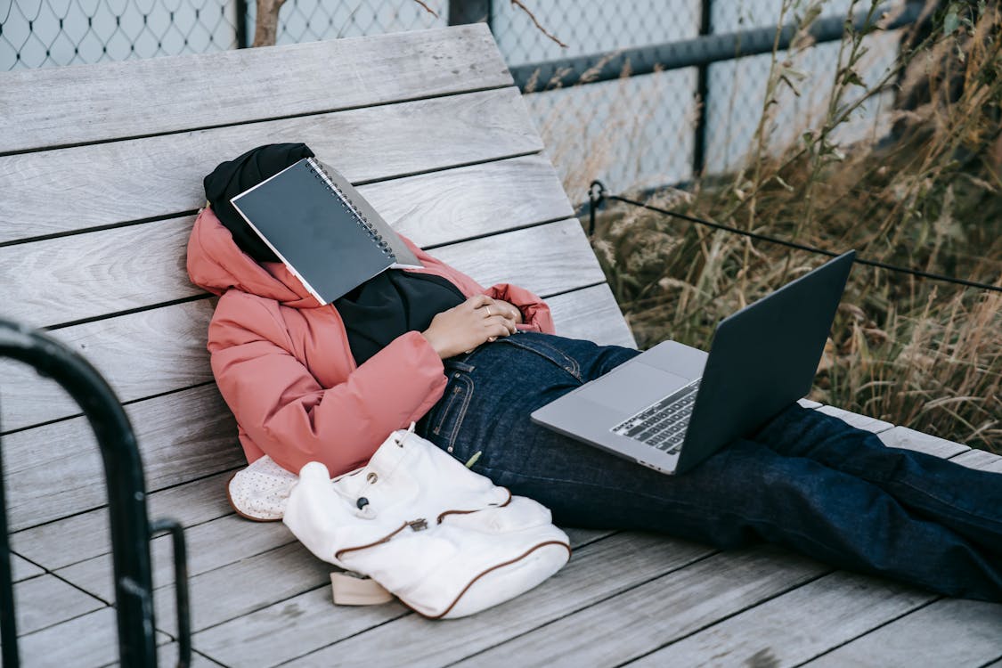 Free Unrecognizable woman with laptop resting on bench in park Stock Photo