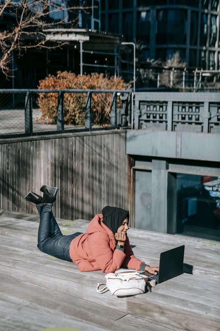 Young Happy Woman Browsing Laptop Lying On Top Of Roof