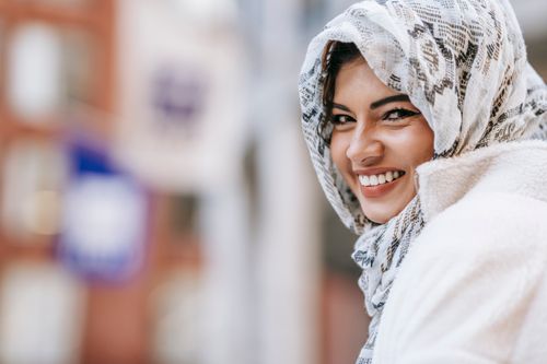 Free Smiling ethnic young lady in warm clothes and hijab in city street in daytime and looking at camera Stock Photo