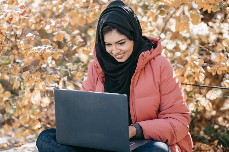 Happy Woman Using Laptop In Autumn Garden