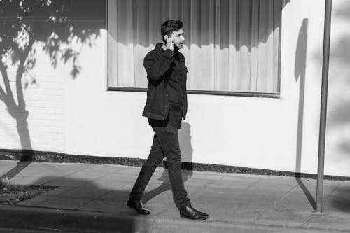 A Man Talking on the Phone while Walking on a Sidewalk