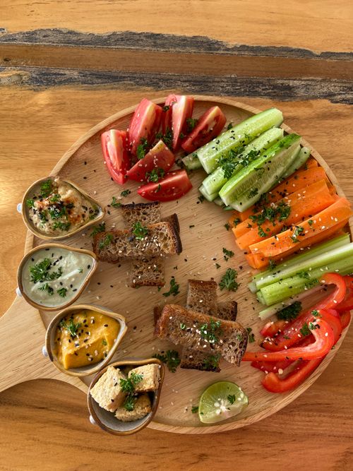 Free Fresh vegan platter featuring vibrant vegetables, dips, and bread slices, perfect for a healthy meal. Stock Photo