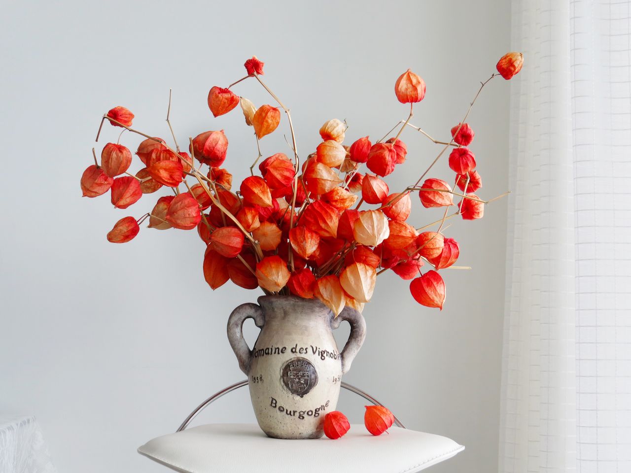 Vibrant orange chinese lantern flowers in a rustic ceramic vase