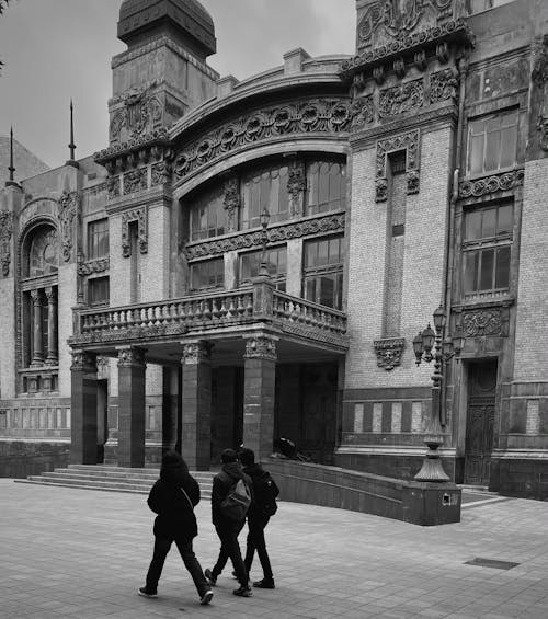 Grayscale Photo of People Walking in front of a Building