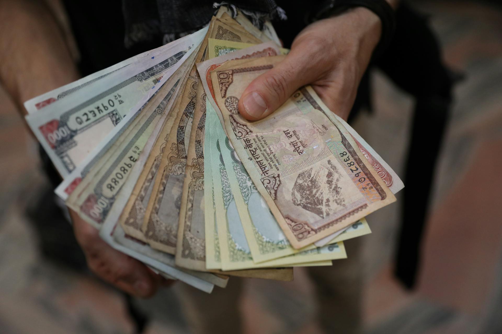 A close-up of hands holding a fan of Nepalese rupee banknotes showcasing various denominations.