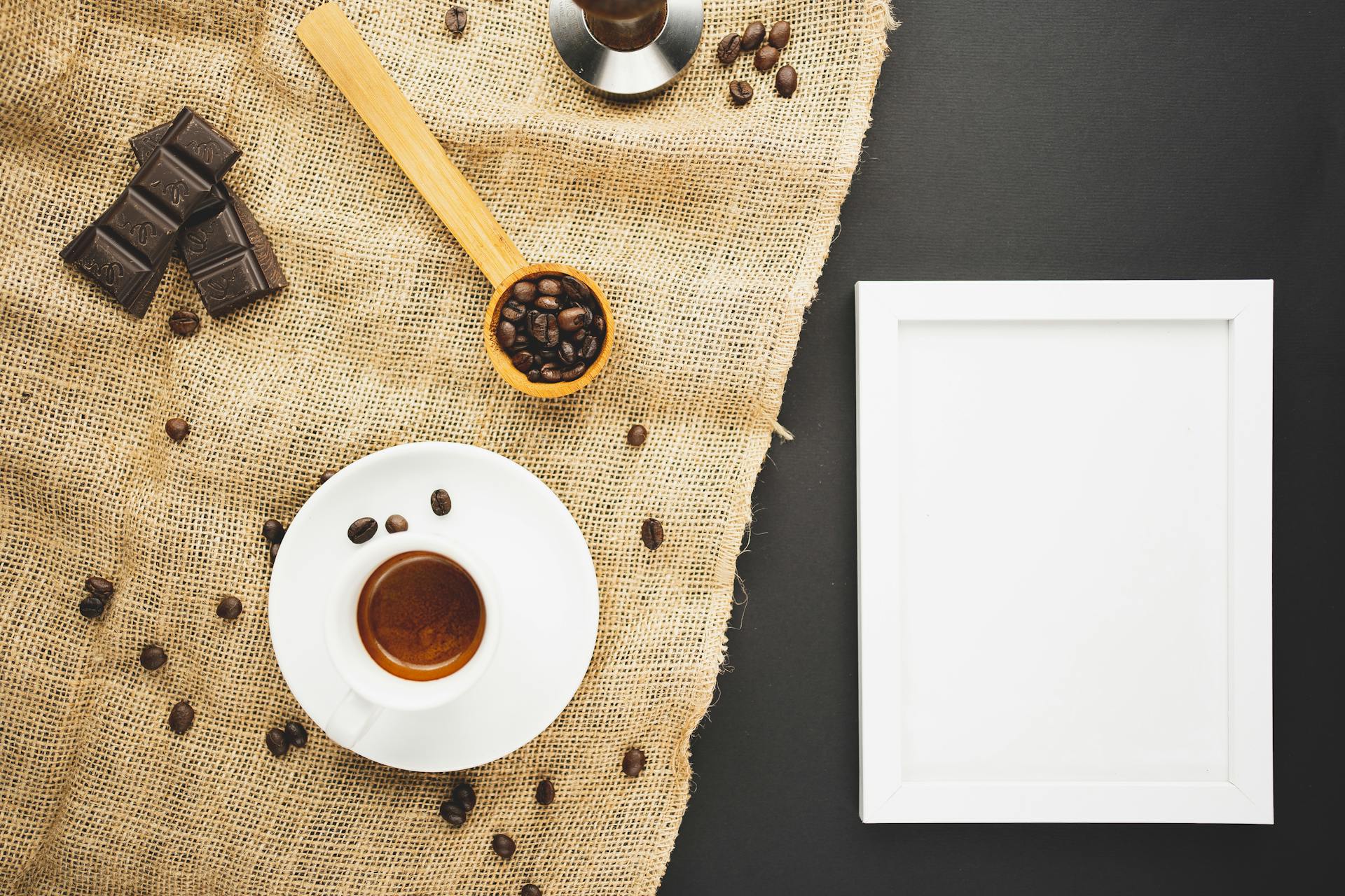Top view of espresso, chocolate, and coffee beans on burlap with empty frame