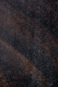 Close-up of a dark textured surface with visible dust, ideal for backgrounds or design uses.