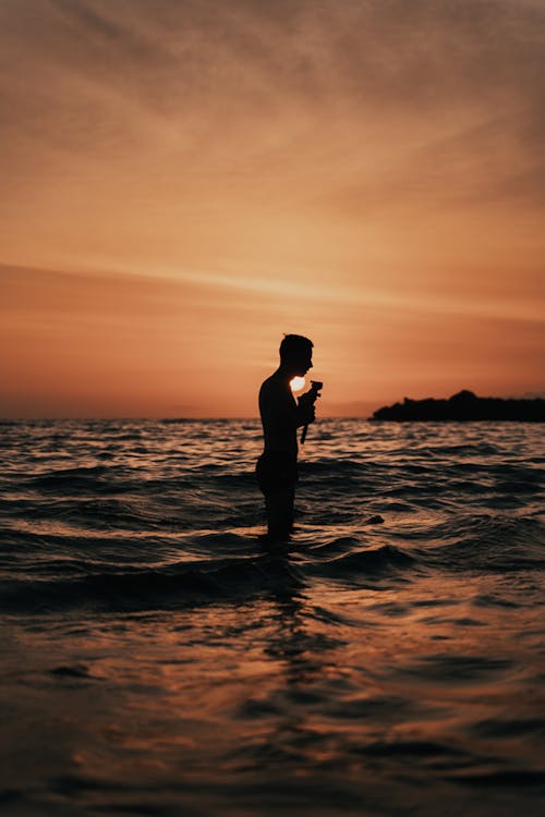 Silhouette of Man Standing on Water  Against Sun