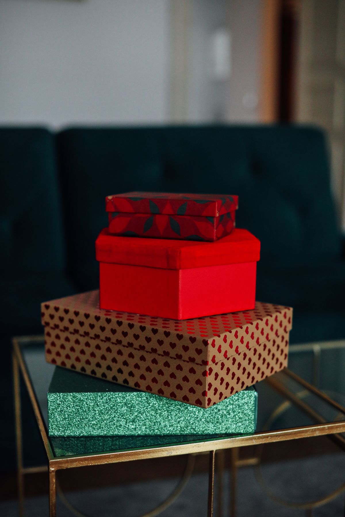 A vibrant stack of wrapped Christmas gift boxes on a glass table in a cozy living room