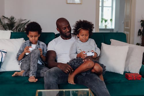 Man In White Crew Neck T-shirt Sitting With His Kids