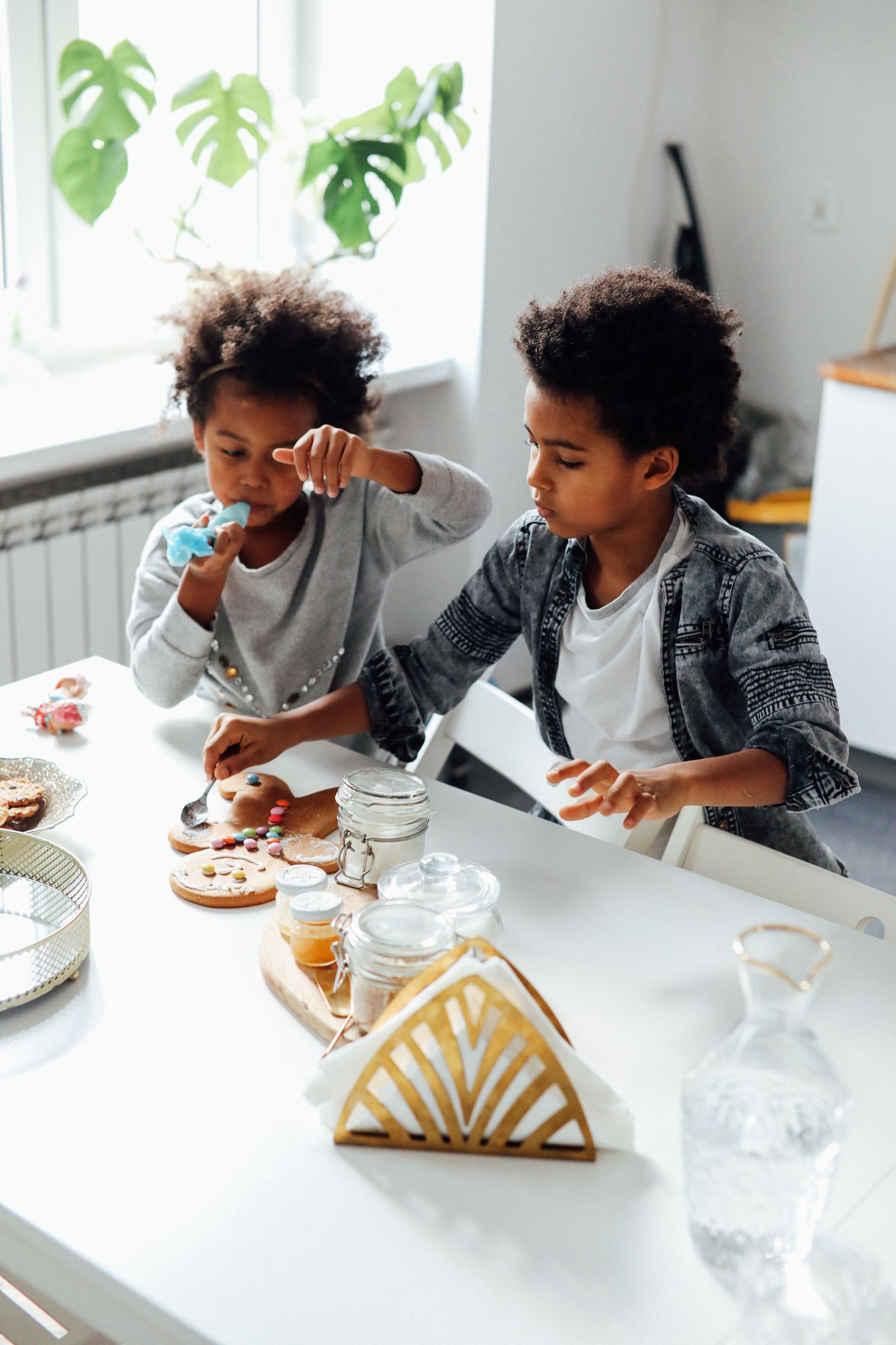 Two children decorating Christmas cookies together in a kitchen.