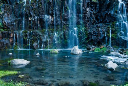Tranquil waterfall cascading into a clear pond surrounded by lush greenery.