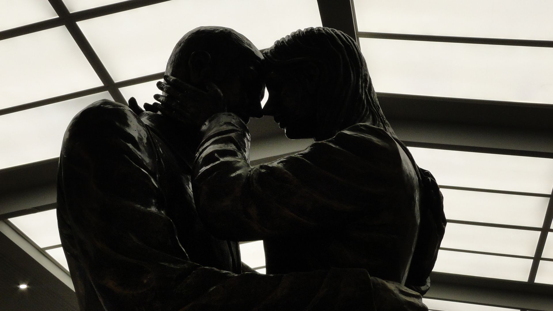 A striking silhouette of a couple's tender embrace captured in a modern bronze sculpture.