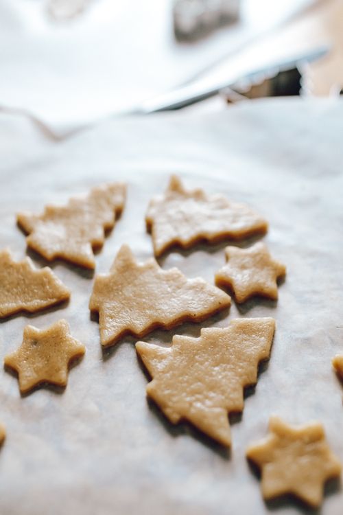 Free Close-up of raw cookie dough cut into festive shapes on parchment paper, ready for baking. Stock Photo