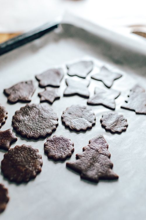 Free Freshly baked chocolate cookies shaped like Christmas symbols on a baking tray. Stock Photo