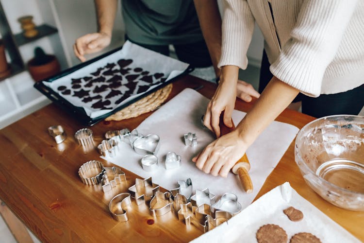 Hands Pressing Down Rolling Pin On White Wax Paper