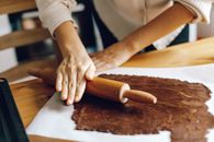 Hand Flattening Brown Dough with Wooden Rolling Pin